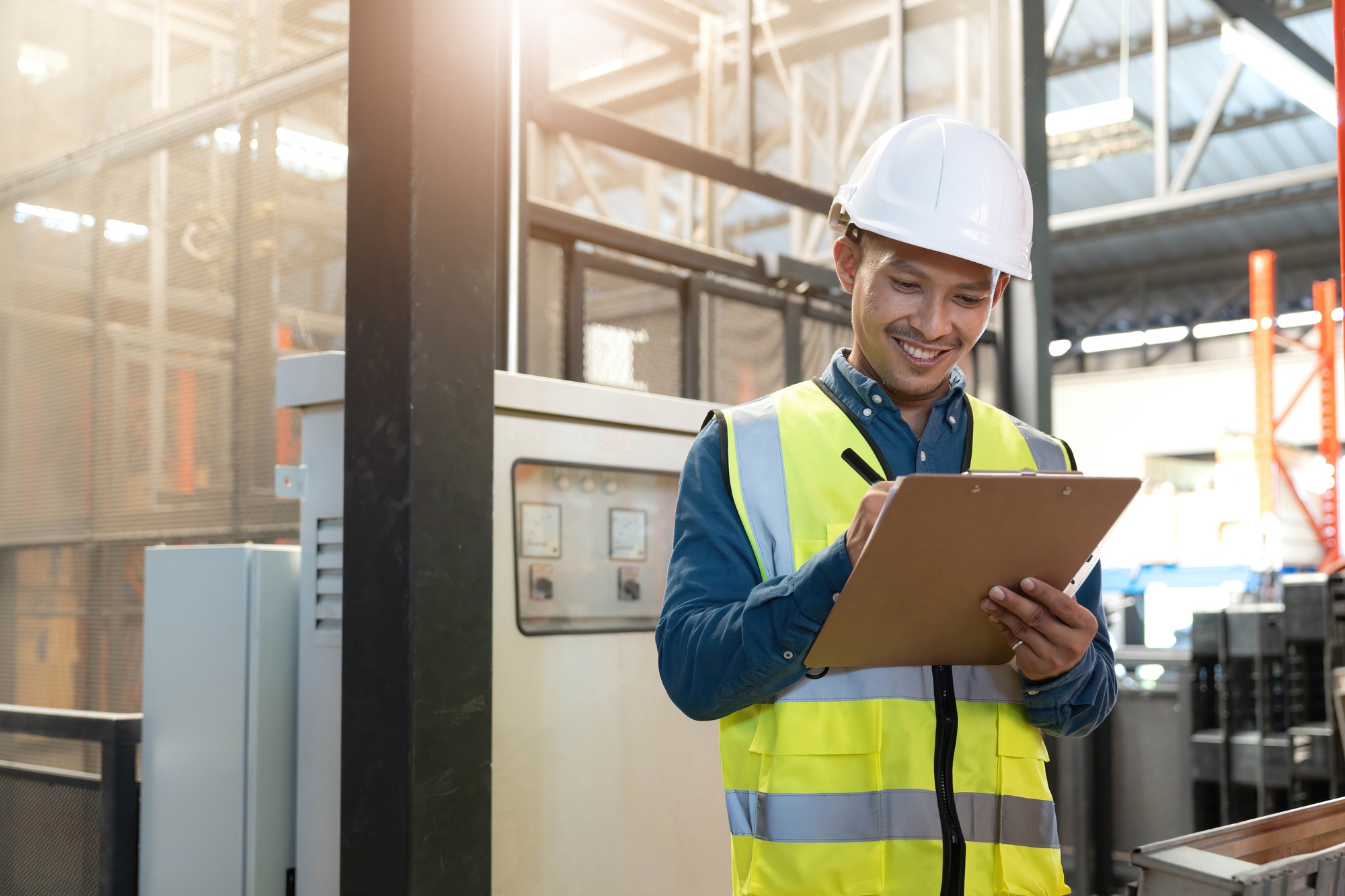 Portrait An Asian warehouse worker in a blue security suit holding clipboard working at store