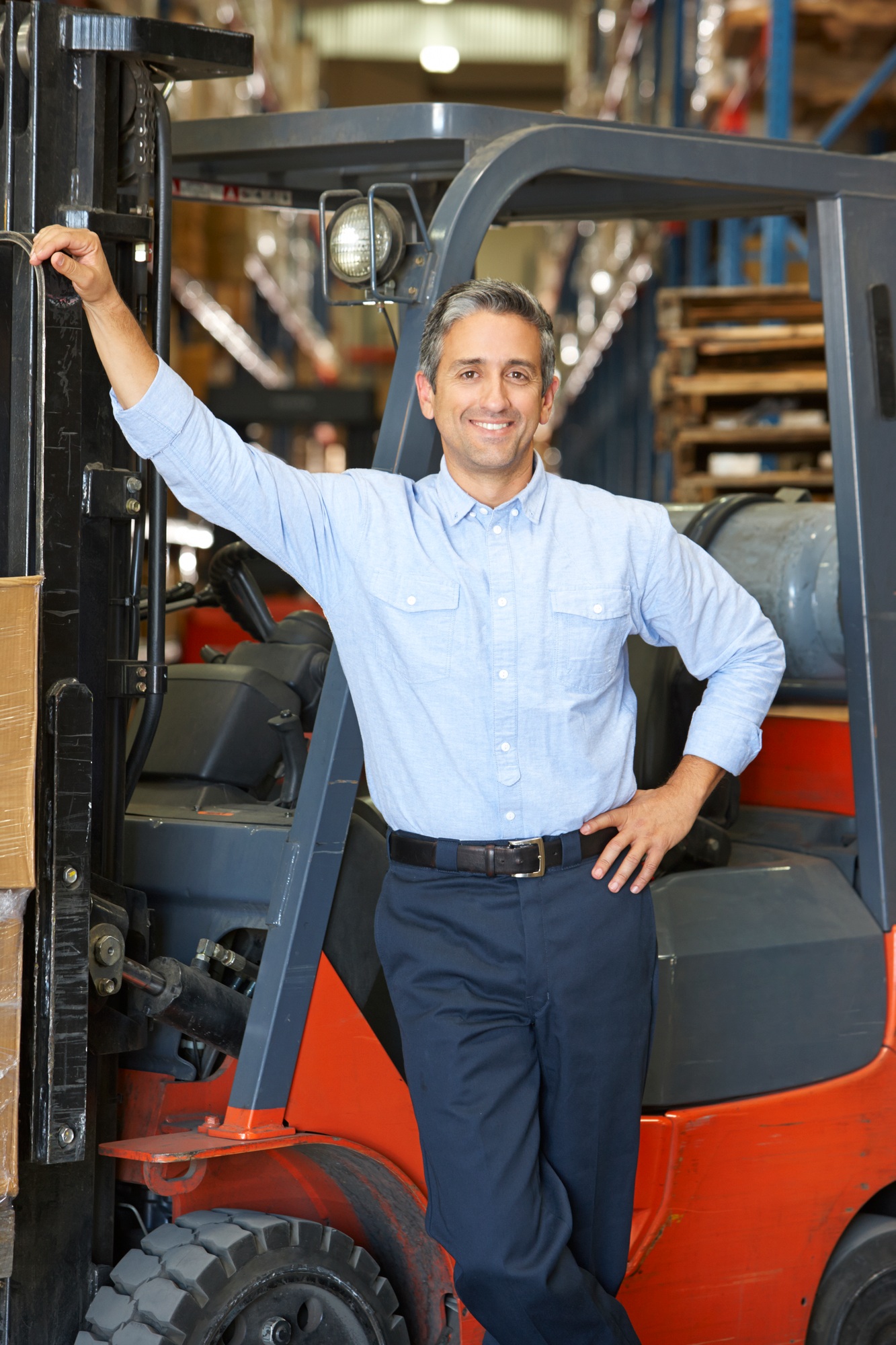 Portrait Of Man With Fork Lift Truck In Warehouse